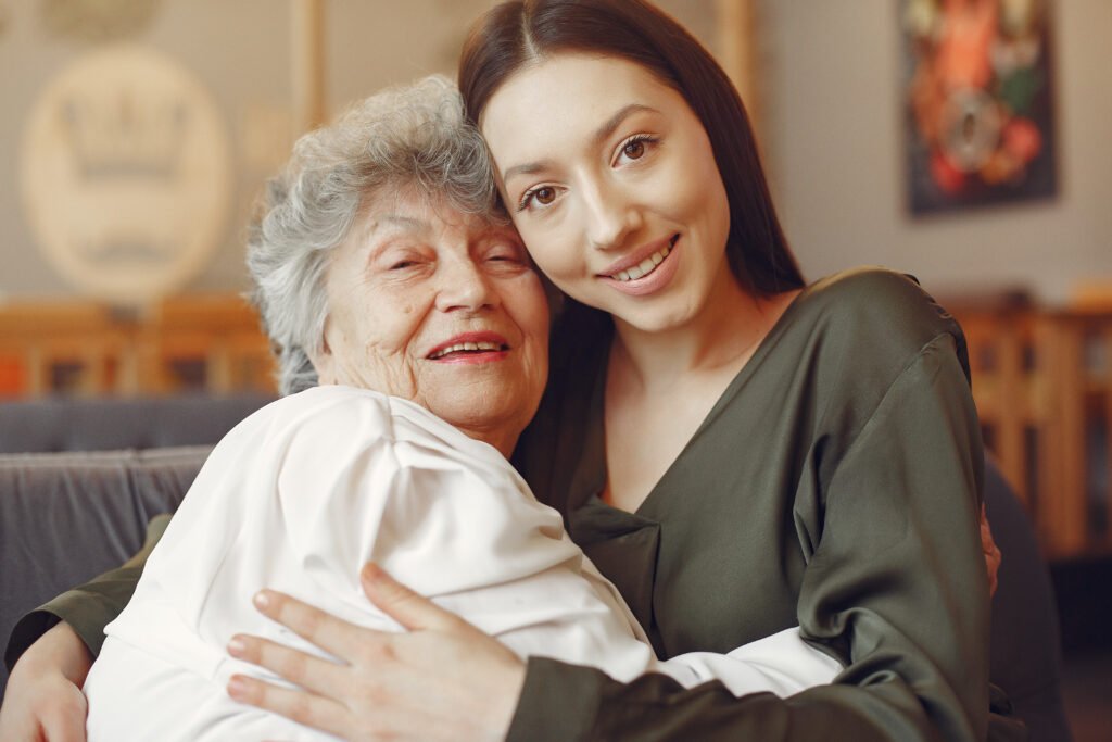 Junge Frau umarmt eine ältere Dame als Teil der Betreuung in Herne